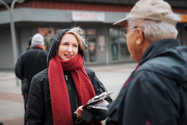 Ines Schwerdtner steht in winterlichtem Outfit auf einem Platz in Lichtenberg und spricht mit einem älteren Herren.